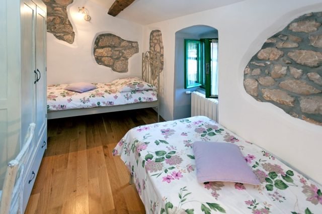 Soba s dva kreveta i izloženim kamenim zidom